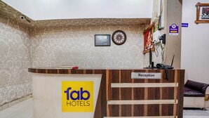 Ein Empfangsschalter mit einem Schild 'fab hotels', einer Uhr und einem 'PhonePe'-Schild an der Wand.