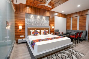 A modern bedroom with a large bed, a sofa, and a desk. - Fabhotel The Valentine (Surat)