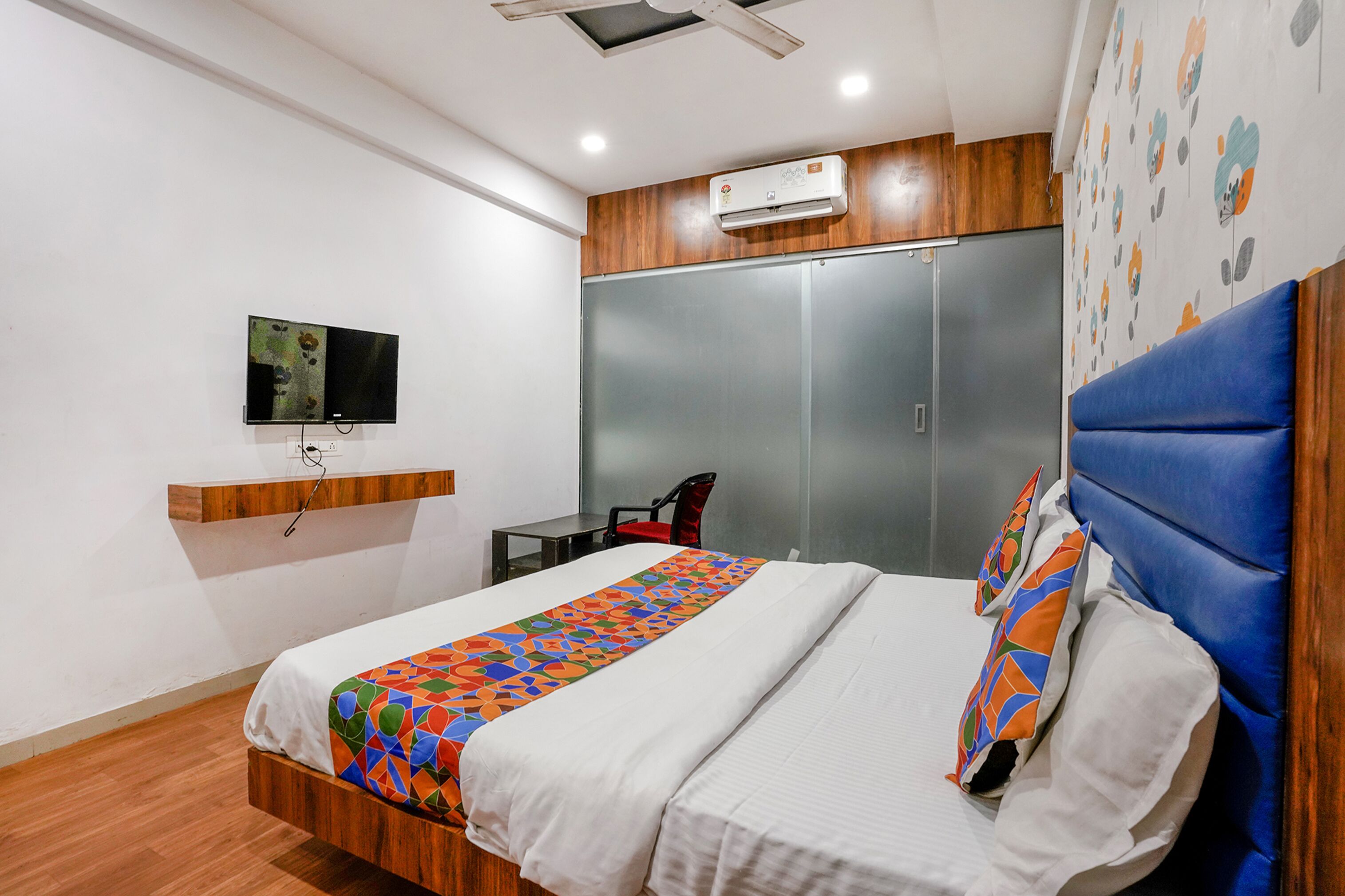Une chambre d’hôtel avec un lit, un téléviseur fixé au mur, une armoire et une petite table.