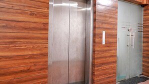 Un ascensor con puertas metálicas y un panel de pared de madera.