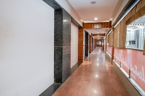 Un pasillo de hotel con suelo de madera, paredes de mármol y una pared roja con texto.