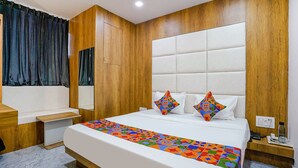 Un hotel moderno con una cama grande, paneles de madera, una mesita de noche y una mesita auxiliar.