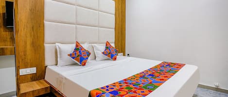 A neatly made bed with a colorful geometric-patterned bedspread, a wooden headboard, and two decorative pillows.