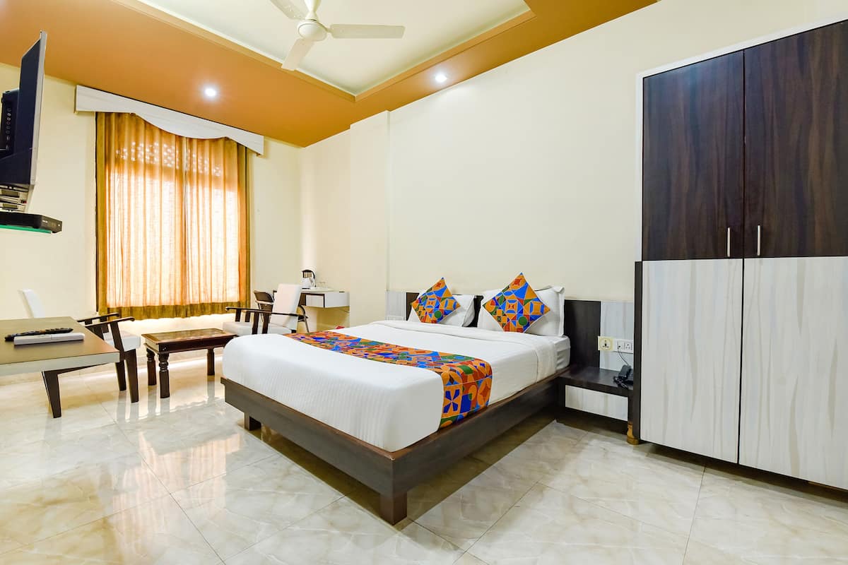 A hotel room with a bed, a desk, a chair, a wardrobe, and a TV.