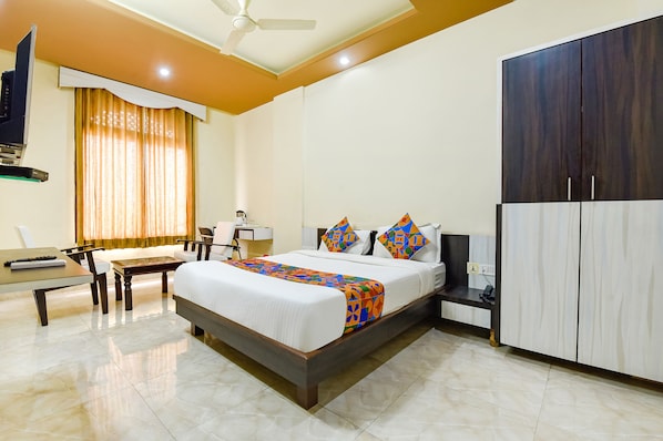 Una habitación de hotel con cama, escritorio, silla, armario y televisor.