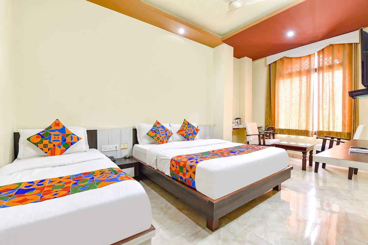 A hotel room with two beds, a desk, and a chair.