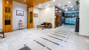 Um hall amplo com teto de madeira, balcão de recepção, sofá e parede estampada.