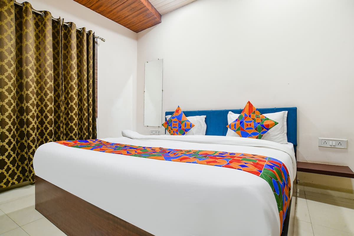 Una cama bien hecha con una colcha colorida, un cabecero azul y almohadas estampadas.