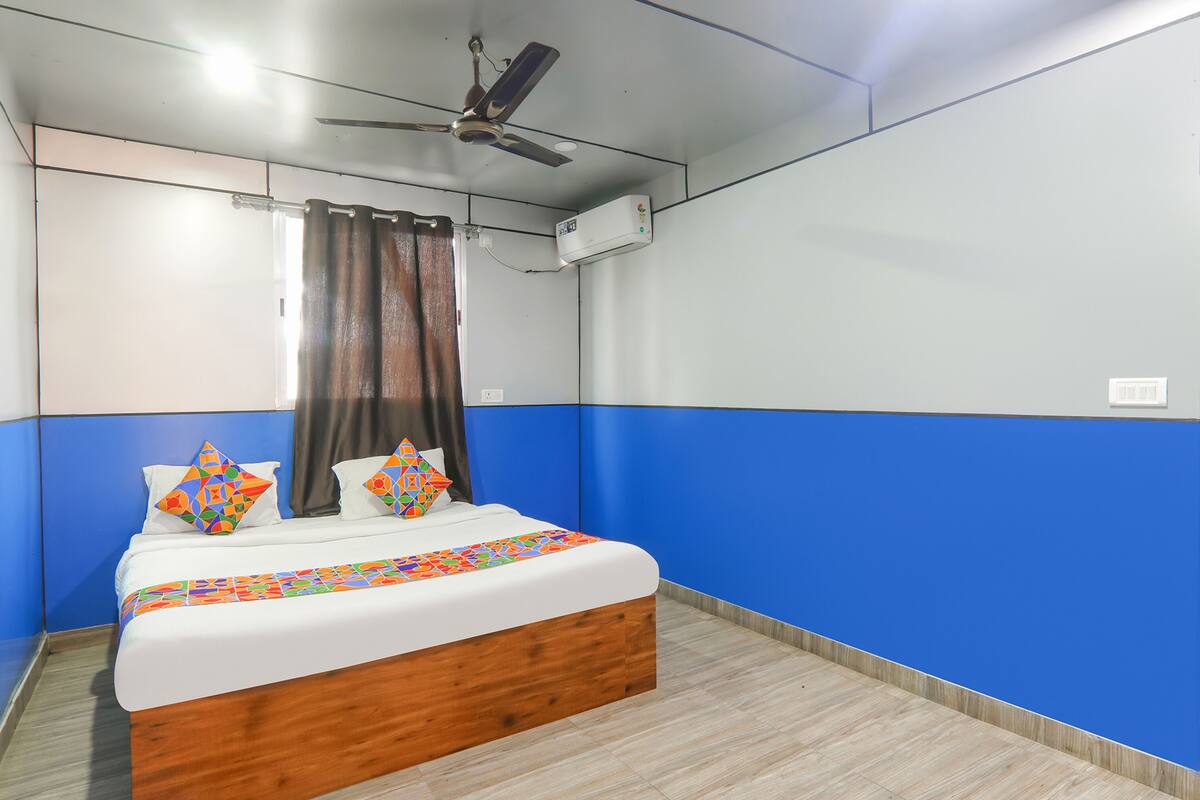 Quarto com cama, cortinas, ventilador de teto e ar condicionado.