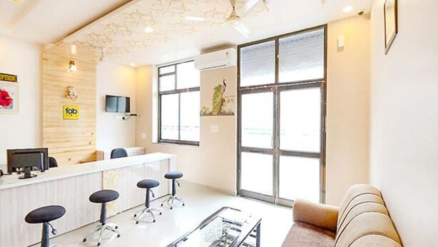 A modern office with a reception desk, multiple chairs, a sofa, and large windows. - Hotel Staybizz by Keymagics (Jaipur)