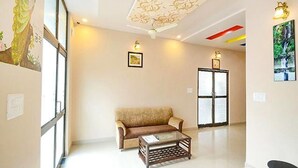 A spacious room with a sofa, a coffee table, and a door with frosted glass panels. - Hotel Staybizz by Keymagics (Jaipur)