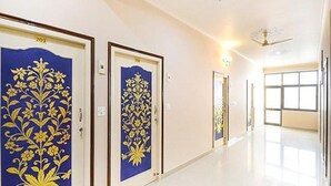 A hallway with doors numbered 203 and 204, featuring blue doors with golden floral designs. - Hotel Staybizz by Keymagics (Jaipur)