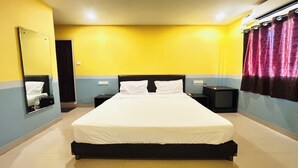 Ein Hotelzimmer mit einem großen Bett, Nachttischen, einem Spiegel und einem Fernseher.