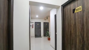 A hallway with doors labeled 305 and 306, a potted plant, and a fire extinguisher. - Fabhotel Paradise Stay Inn (Nagpur)