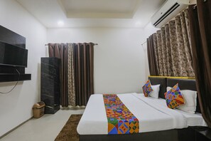 A hotel room with a bed, a flat-screen TV mounted on the wall, an air conditioning unit, and a window with curtains. - Fabhotel Paradise Stay Inn (Nagpur)