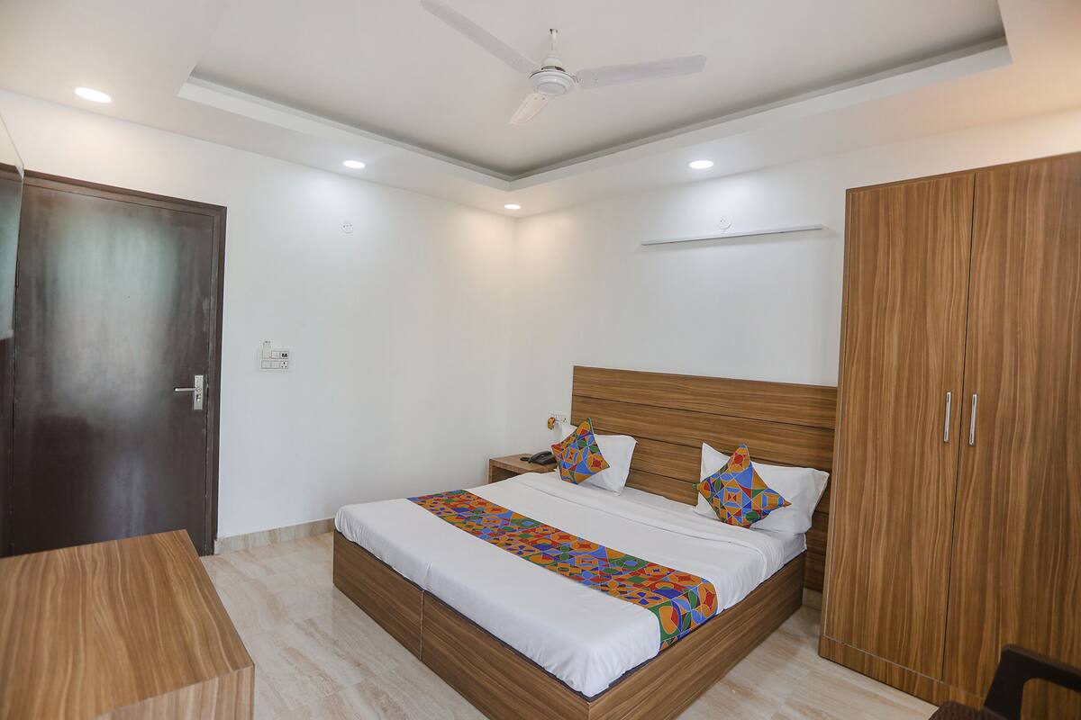 Un dormitorio con una cama de madera, una mesita de noche, un armario y un ventilador de techo.