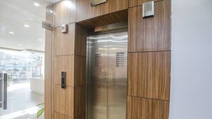 An elevator with a wooden panel design and a metallic interior. - Fabhotel Unique Stay (Noida)