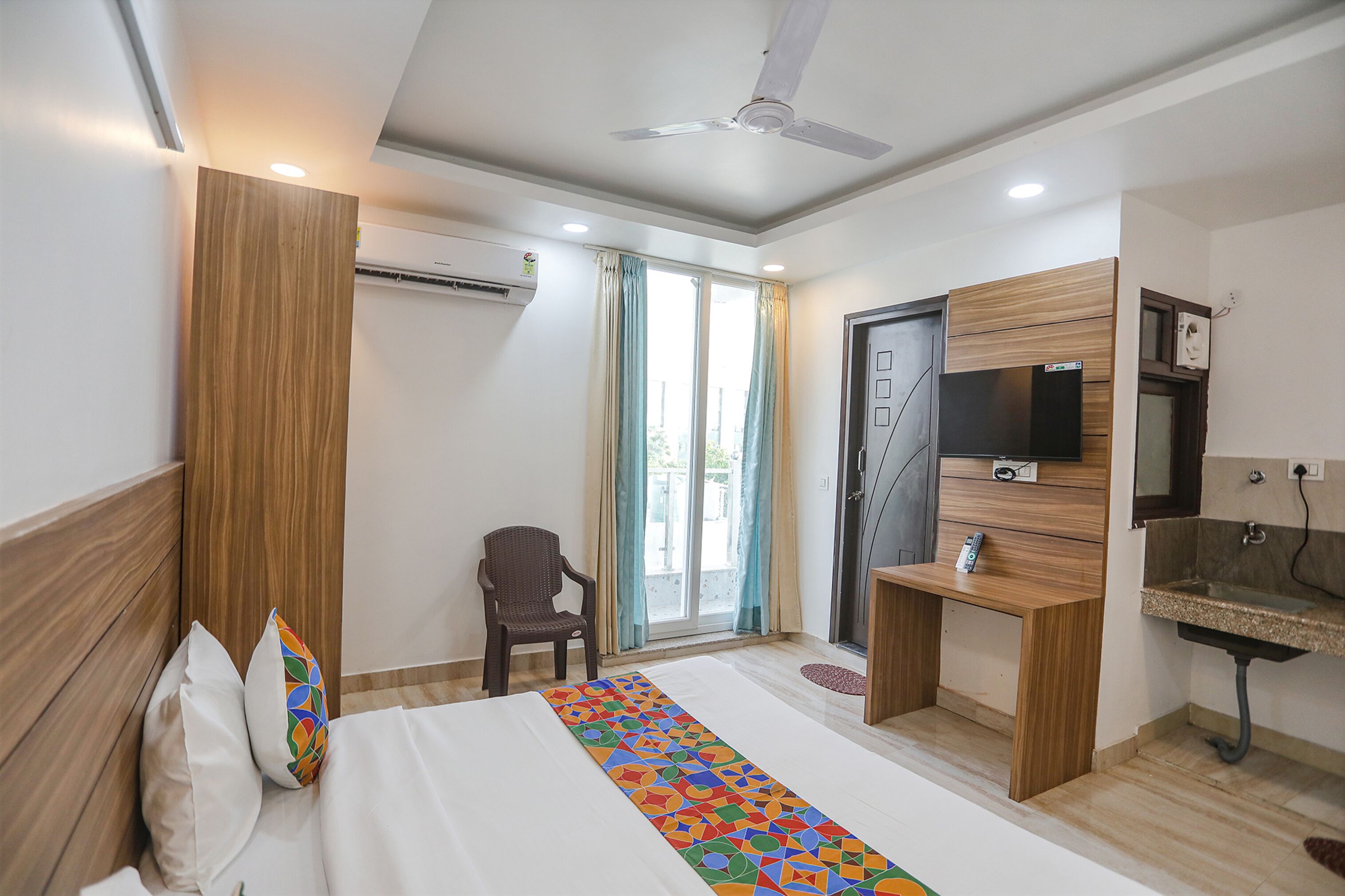 Habitación de hotel con cama, escritorio, silla, televisor y baño.