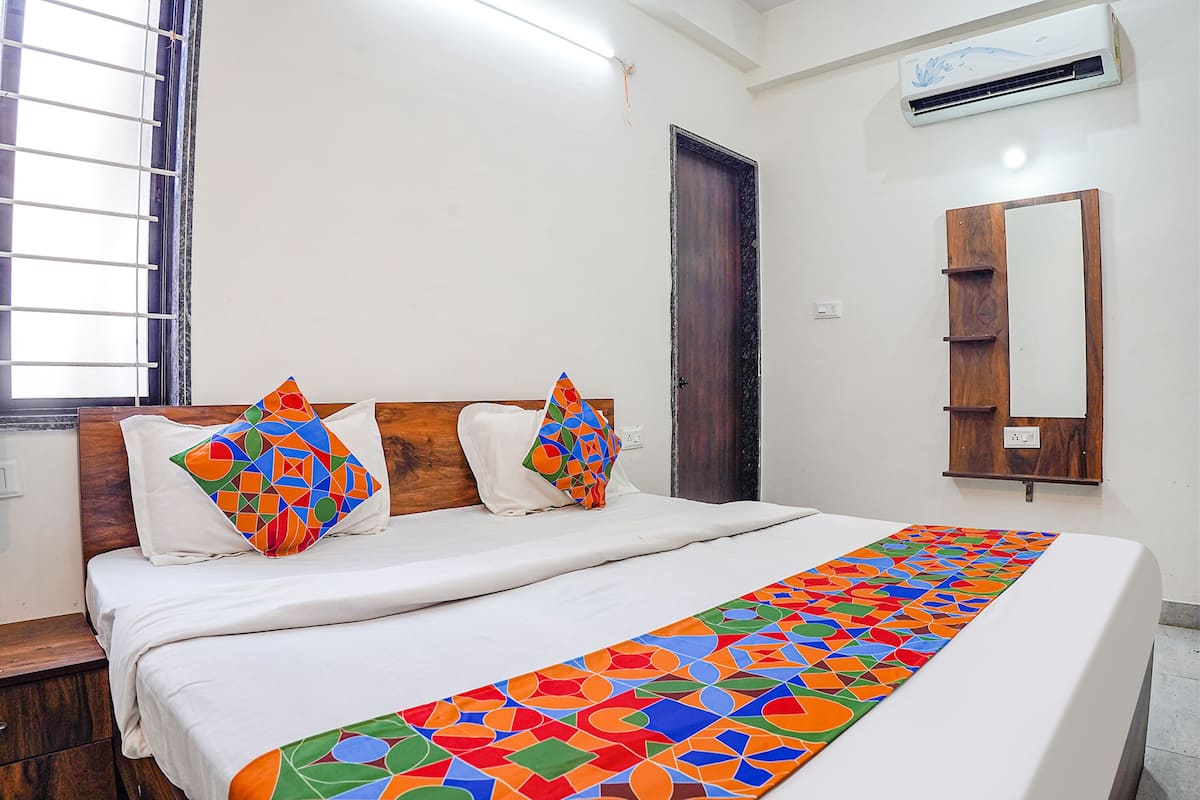 A neatly made bed with a colorful geometric-patterned bedspread, a wooden headboard, and two decorative pillows.