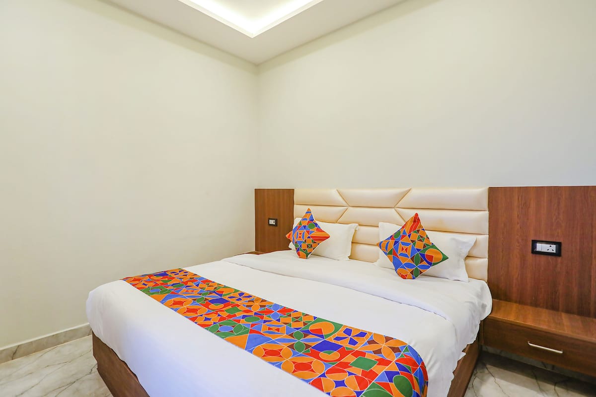 A neatly made bed with a colorful geometric-patterned bedspread and two decorative pillows.