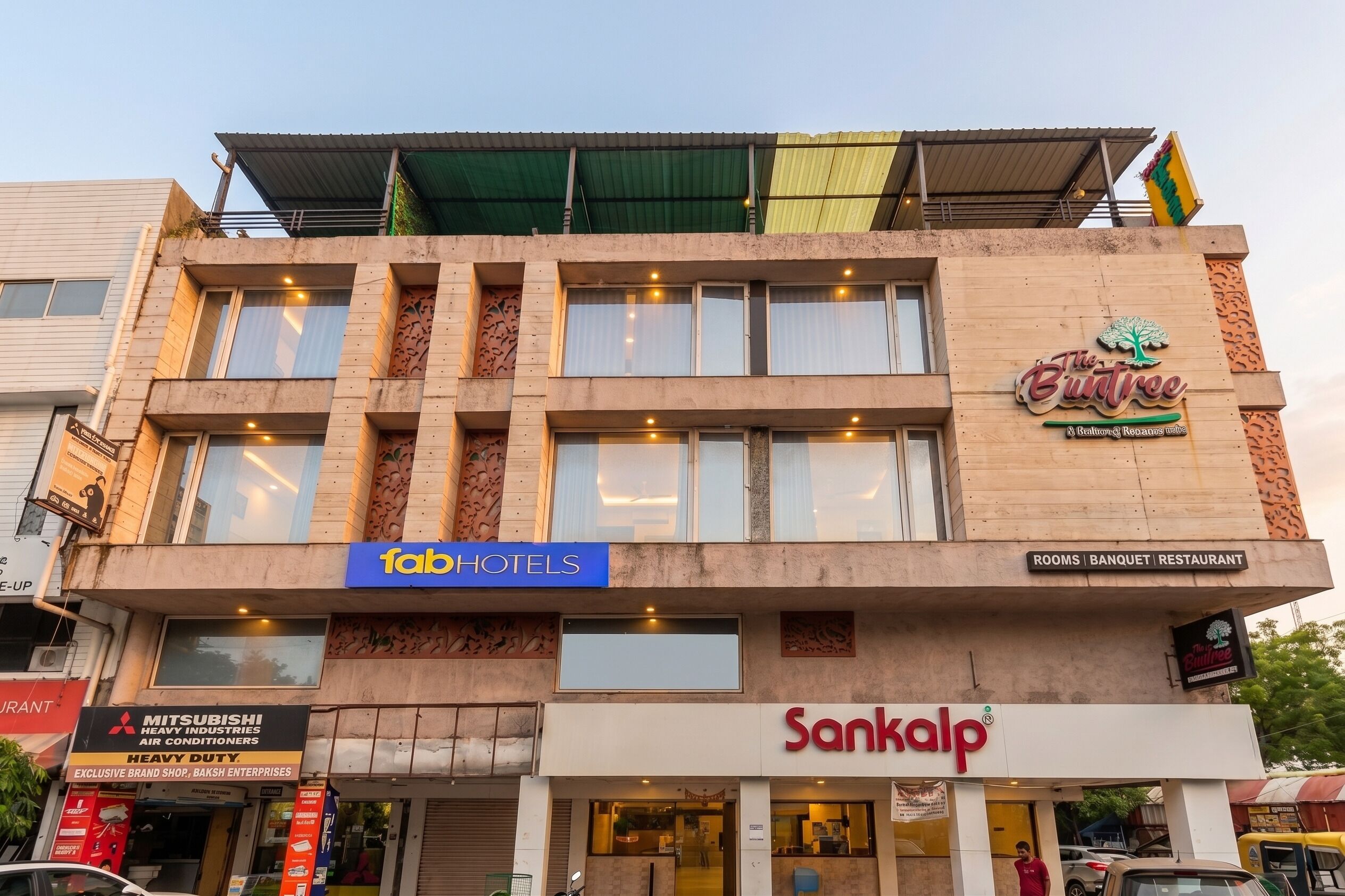 Un hotel con un letrero que indica 'fab hotels' y 'Sankalp' en la planta baja.