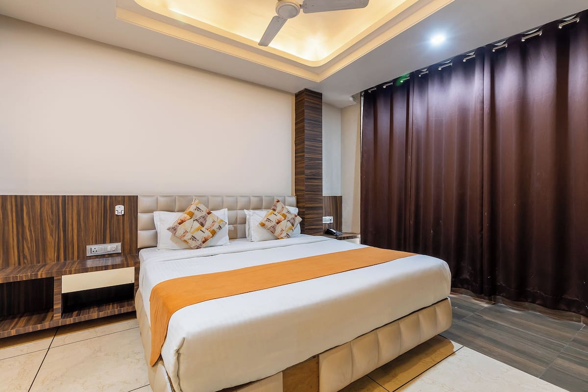 Quarto moderno com uma cama grande, ventoinha no teto e cortina escura.