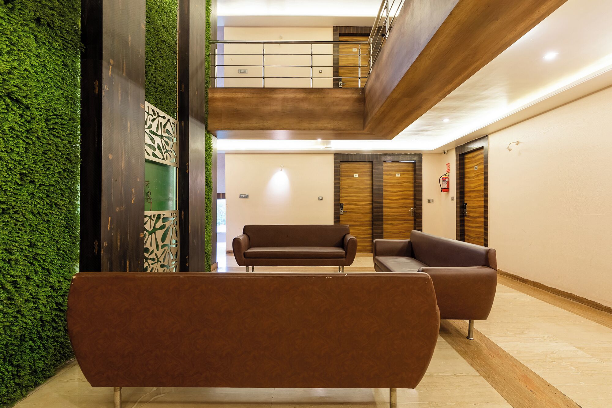 A lobby with a green wall, two sofas, a staircase, and wooden doors.
