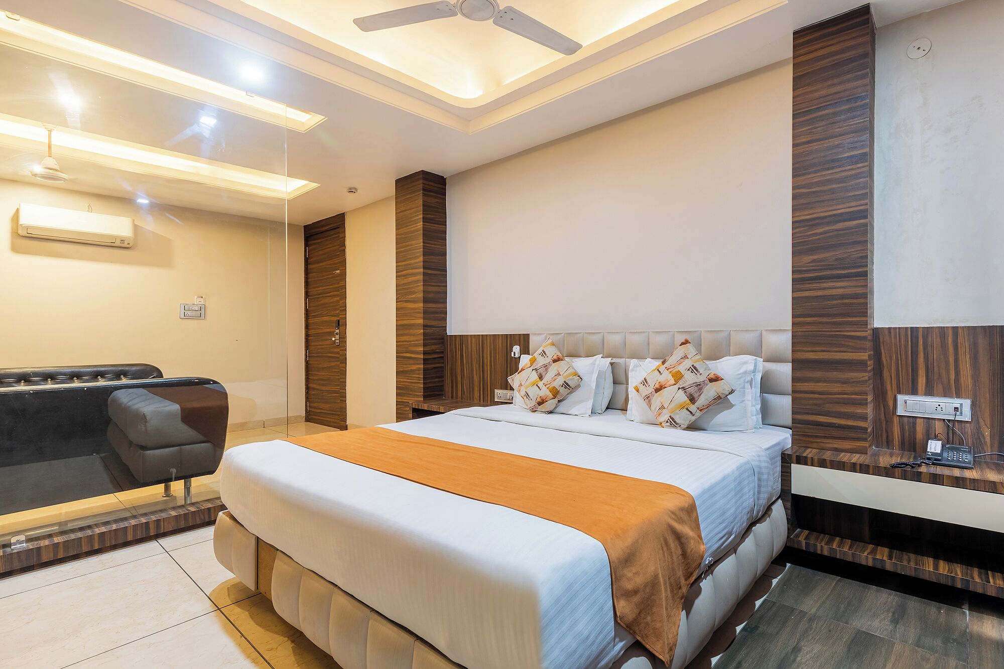 A modern hotel room with a large bed, a desk, and a ceiling fan.