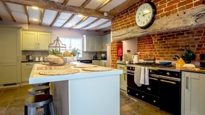 Una cocina con una isla central, un muro de ladrillo y un reloj.