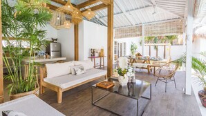 Amplia sala de estar con techo de madera, un sofá, una mesa de centro y un comedor con una mesa y sillas.