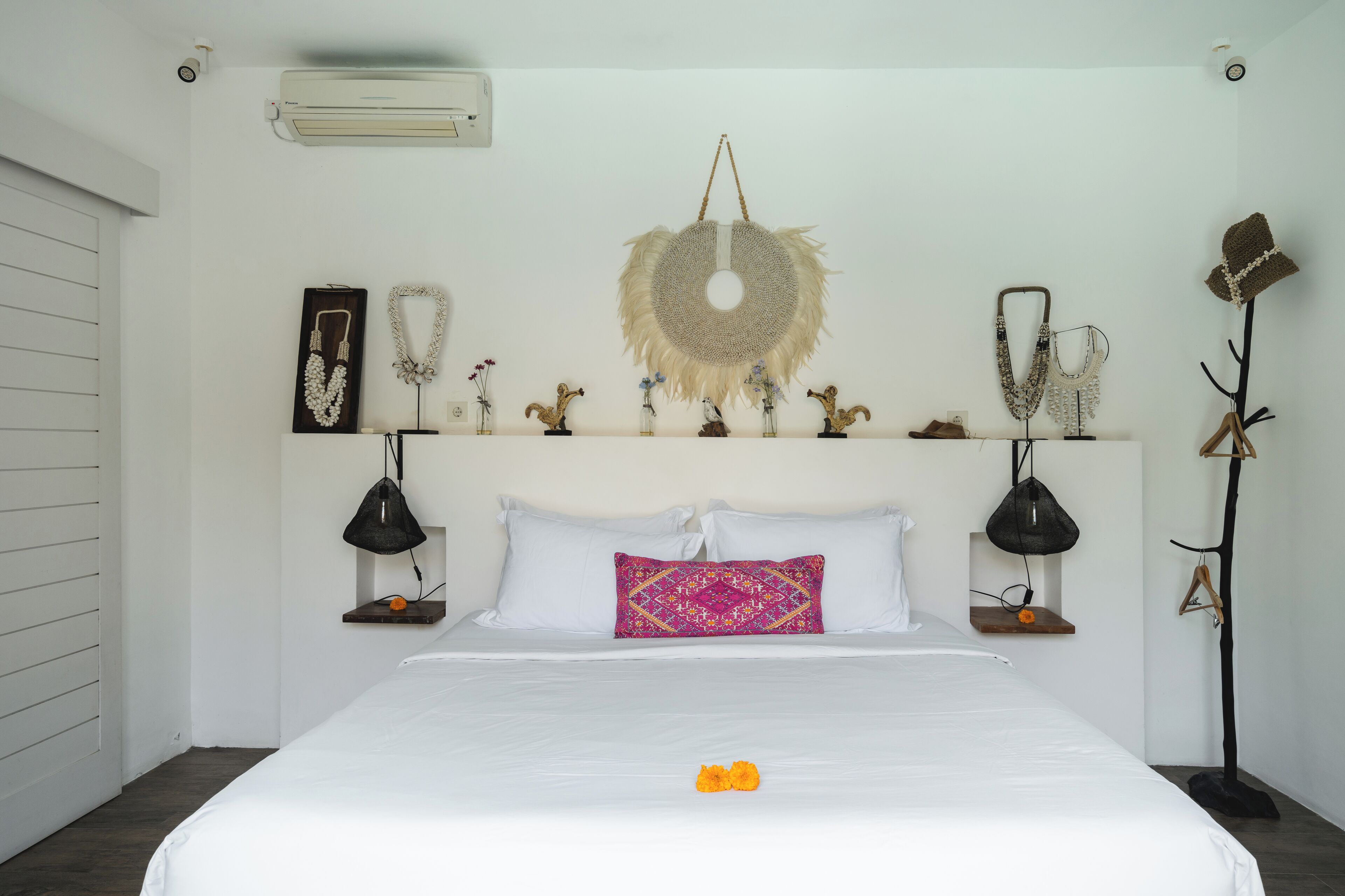 A neatly arranged hotel room with a bed, decorative wall hanging, and a floor lamp.