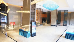 A spacious lobby with a modern chandelier, a reception desk, and a seating area with a blue tablecloth. - Langson Dongguan - Dalang Songshan Lake (Dongguan)