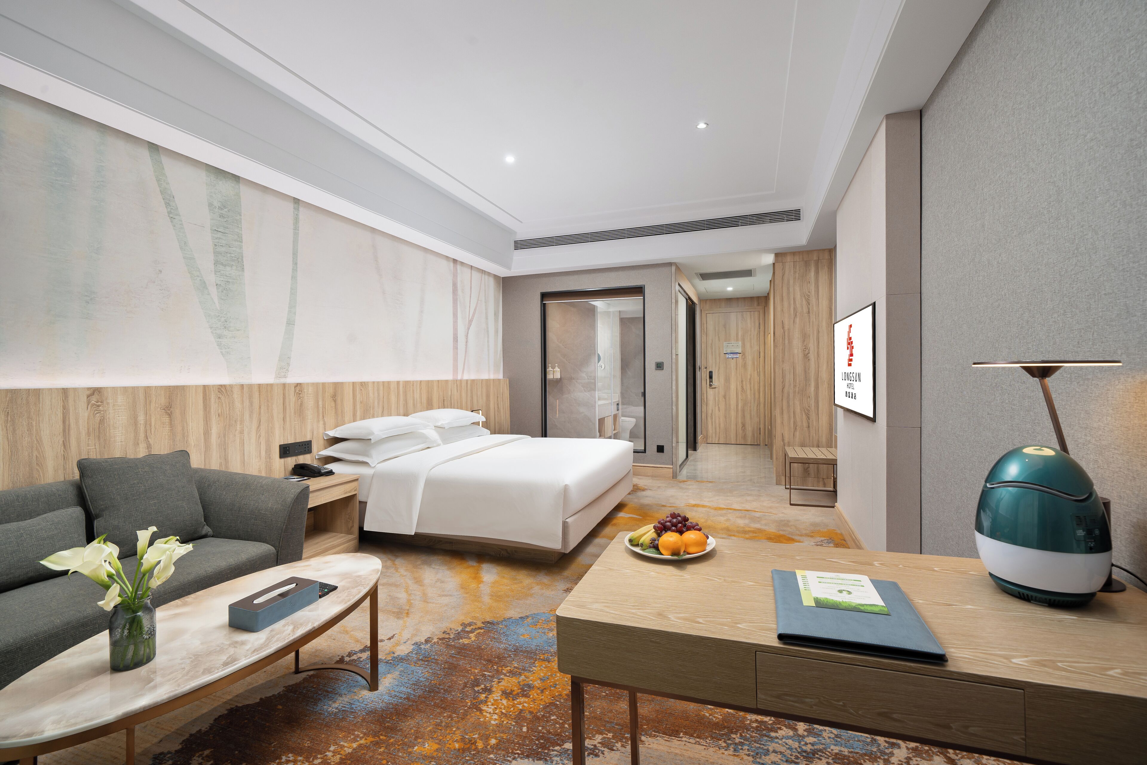 A modern hotel room with a bed, a sofa, a desk, and a coffee table.