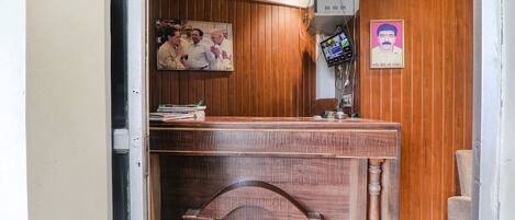 Una recepción con detalles de madera, un televisor montado encima y un cartel de 'fab hotels'.