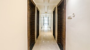 Un pasillo con puertas de madera y suelo claro que conduce a una habitación luminosa al final.