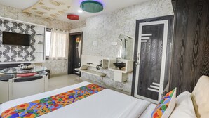 A hotel room with a bed, a desk, a TV, and a bathroom. - FabHotel Greenland Classic (Bhubaneshwar)