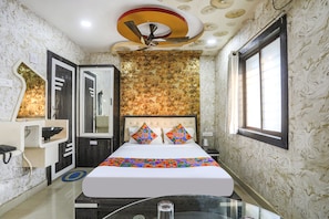 A hotel room with a bed, a ceiling fan, a window, and a mirror. - FabHotel Greenland Classic (Bhubaneshwar)