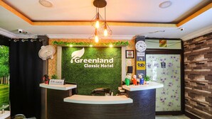 A reception desk at Greenland Classic Hotel with a green wall, a clock, and a fan. - FabHotel Greenland Classic (Bhubaneshwar)