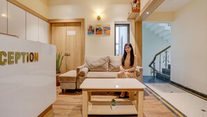 A reception area with a reception desk labeled "RECEPTION," a beige sofa, a small table, and a potted plant. - Fabhotel Heritage Palace (Chhatrapati Sambhajinagar)