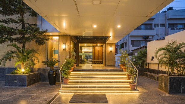 A hotel entrance with a staircase, potted plants, and a well-lit pathway. - Fabhotel Heritage Palace (Chhatrapati Sambhajinagar)