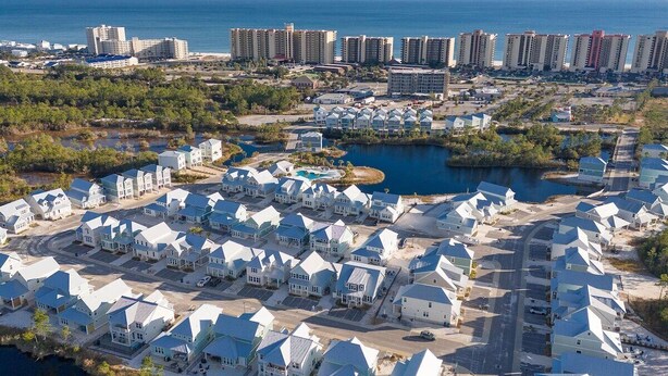 A coastal residential area with multiple-story buildings, a marina, and a large body of water. - Sea La Vie- Dog Friendly Cottage in Orange Beach (Orange Beach)