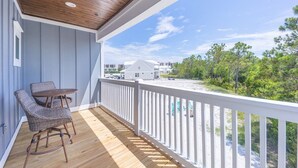 A wooden deck with a white railing, wicker chairs, and a table. - Sea La Vie- Dog Friendly Cottage in Orange Beach (Orange Beach)