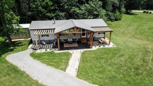 Eine Lodge mit überdachter Terrasse, einem Schotterweg und einem Rasen.