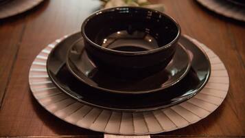 A dark-colored bowl on a matching plate, placed on a wooden table with a striped placemat.