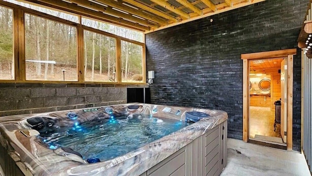 Een wellnessruimte met een hottub, houten plafond en uitzicht op de omgeving.