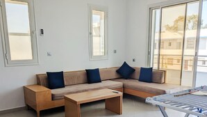 Uma sala de estar moderna com um sofá modular, uma mesa de centro de madeira e um varal de metal.