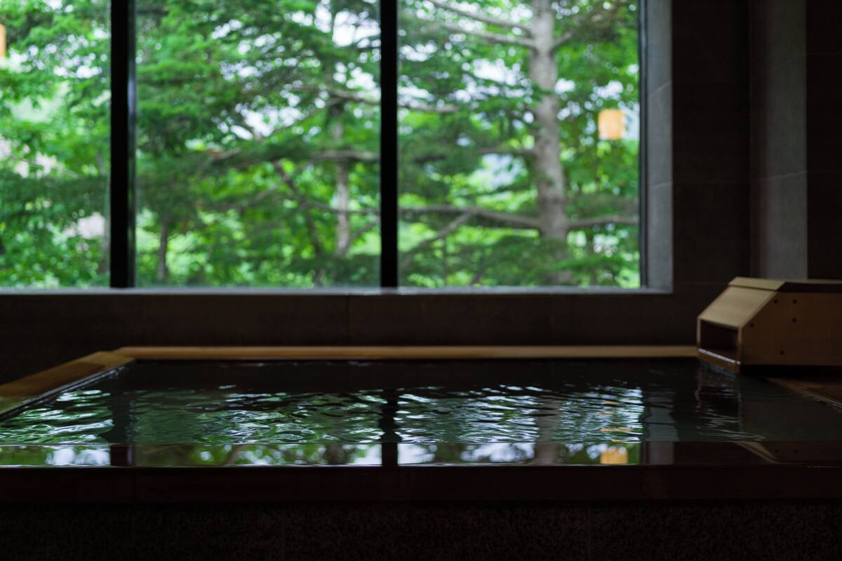 A room with a large window, a wooden bench, and a small wooden structure.