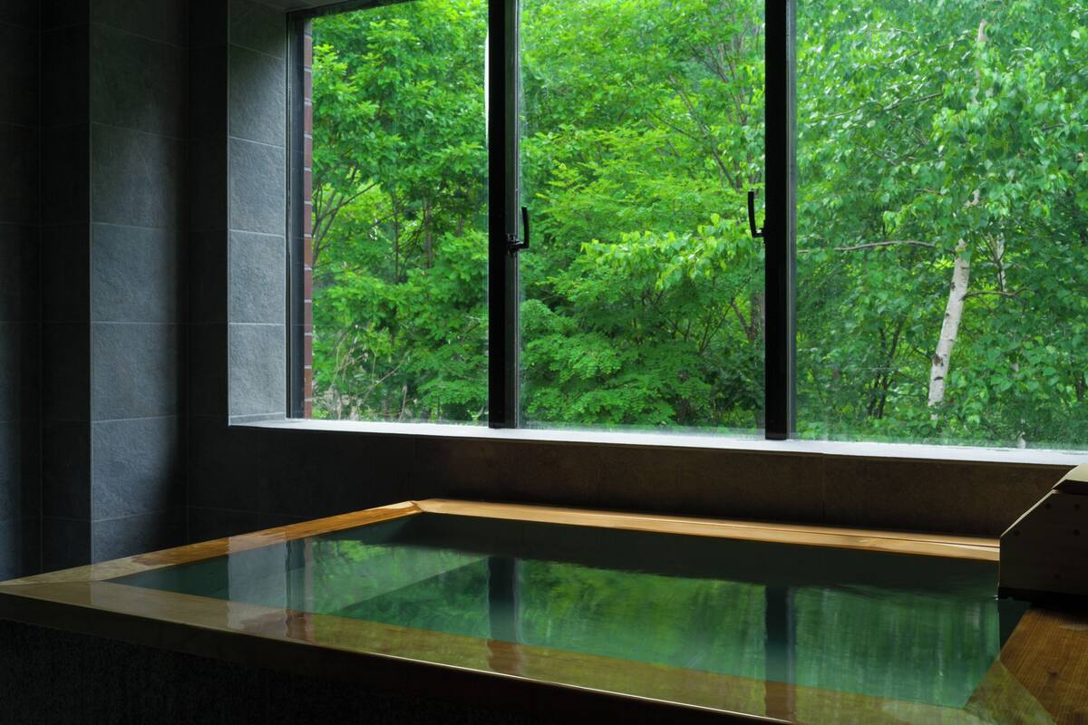 A room with a large window overlooking a dense forest.
