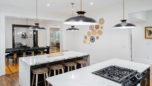 A modern kitchen with a central island, pendant lighting, and a dining area with chairs. - Historic Gem in the Heart of Norcross (Norcross)