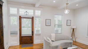 A living room with a grey sofa, a coffee table, and a lamp. - Historic Gem in the Heart of Norcross (Norcross)